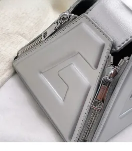 Detailed view of silver PU handbag featuring geometric triangle structure and metal zipper