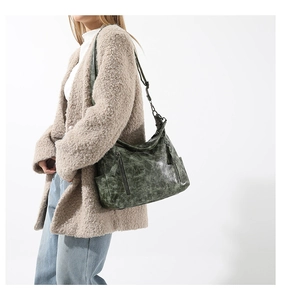Detail of dark green oil-wax leather shoulder bag with vintage texture and zipper pockets