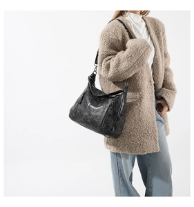 Close-up of black retro shoulder bag with metallic zipper pockets and textured leather detail