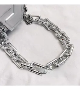 Detail of trendy silver PU handbag featuring a thick square metal chain and sleek zipper