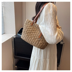 Close-up of woven straw shoulder bag with diamond texture and brown leather strap