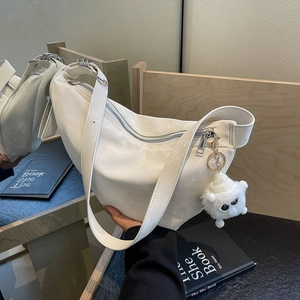 Minimalist white crescent shoulder bag with soft matte texture and plush monster charm