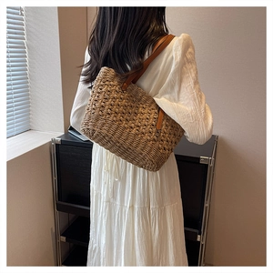 Detail of woven straw tote bag with brown leather handles worn with a white dress