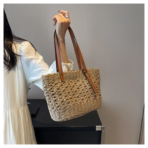 Detailed texture of hollow woven straw tote bag with brown faux leather handles