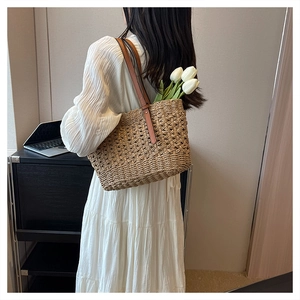 Detail of light brown woven straw shoulder bag featuring an elegant hollow-out texture