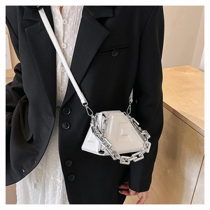 Close-up of a white geometric mini handbag with a chunky silver chain and embossed texture