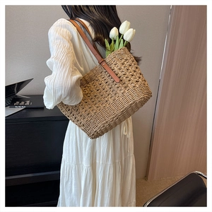 Detail of hand-woven straw tote bag with brown leather straps and summer aesthetic