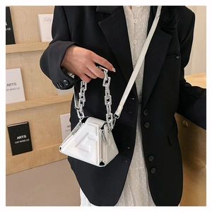 Detailed macro view of white triangular PU handbag with embossed G logo and silver chain