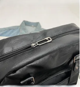 Detail of smooth black leather texture featuring a unique silver safety pin zipper pull