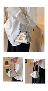 Macro view of silver geometric tote bag with embossed letter G and metal chain strap