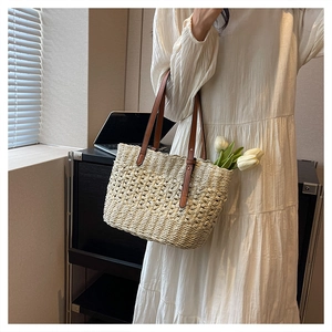 Detail view of woven hollow design straw beach bag with premium brown leather handles