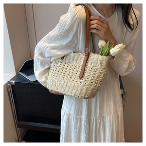 Detailed grid-weave texture of off-white straw beach bag with brown leather shoulder strap