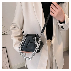 Detail of black geometric PU leather handbag with embossed G and silver chain strap