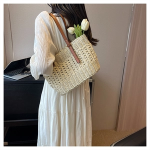 Detail of straw woven tote bag with brown leather handles and decorative white tulips