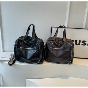 Detail of high-capacity PU leather tote bags in black and dark brown with silver hardware