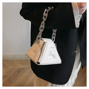 Detail of white geometric triangle bag with embossed G logo and silver chain handle