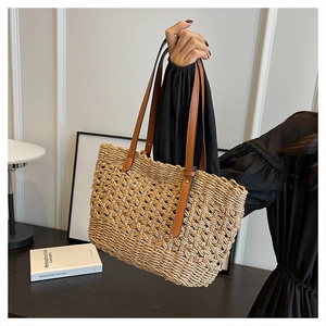 Close-up of hollow woven paper straw tote bag with brown faux leather shoulder strap