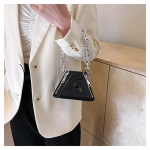 Detail of black triangular PU leather handbag with silver chain and embossed G logo