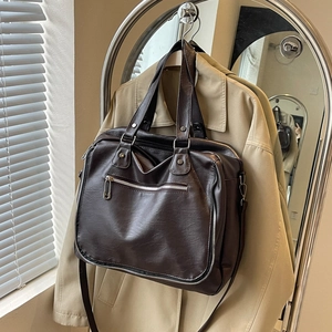 Detailed view of dark brown messenger bag with silver zippers and a vintage leather texture