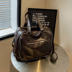 Detail of dark brown messenger bag with silver hardware and adjustable shoulder strap