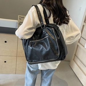Detailed side view of black leather messenger bag featuring silver zippers and large capacity