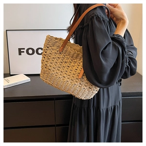 Detailed shot of hollowed-out straw woven tote bag with reinforced brown leather straps