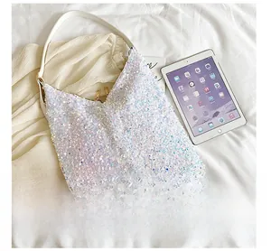 Detail of sequin tote bag with leather strap next to tablet for size comparison