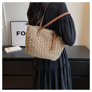 Detail showing the woven texture and brown leather straps of the beach shoulder bag