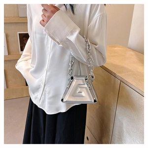Detail of silver mirror PU handbag featuring embossed G logo and chunky metal chain