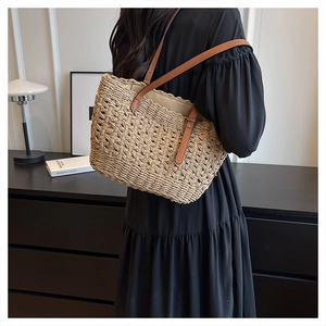 Detail of summer woven straw tote bag with adjustable brown leather strap shown on shoulder