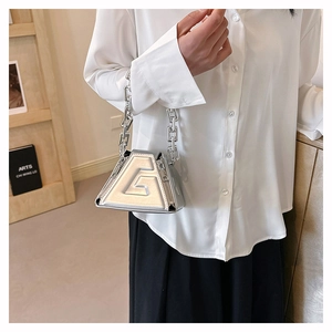 Detailed close-up of a silver triangular mini handbag with a metallic chain strap