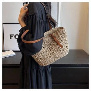 Detail shot of handwoven straw beach bag with brown leather handles and textured weave