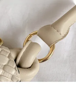 Gros plan d'un sac à main beige en similicuir tressé avec anneaux métalliques dorés