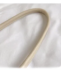 Détail de la bandoulière en similicuir beige avec coutures soignées et texture lisse