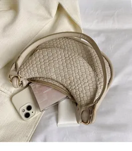 Détail du sac croissant tressé beige montrant la texture du cuir et le rangement interne