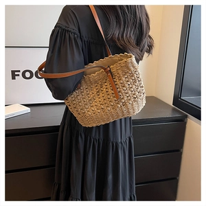 Detail of hand-woven straw shoulder bag with brown leather strap and wavy texture