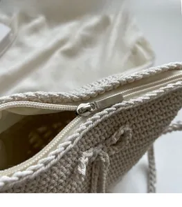 Detail eines silbernen Metallreißverschlusses und Webstruktur einer cremefarbenen Tasche