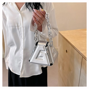 Detailed view of a silver geometric handbag with chunky metal chain and embossed G detail