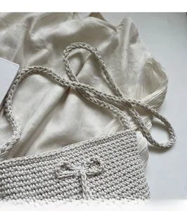 Detail der handgewebten cremefarbenen Tasche mit Stricktextur und Zierschleife