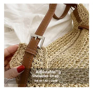Close-up detail of woven straw tote with adjustable brown leather strap and metal buckle
