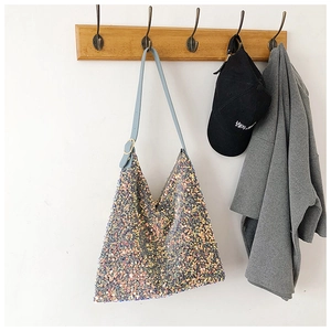Detailed close-up of a blue sequined hobo bag with iridescent finish hanging on a hook