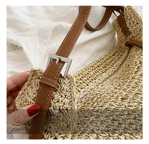 Detail view of woven straw tote featuring brown leather strap and silver metal buckle