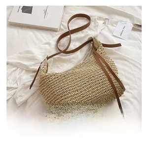 Detail of straw woven tote bag featuring brown leather strap and decorative fringe tassel