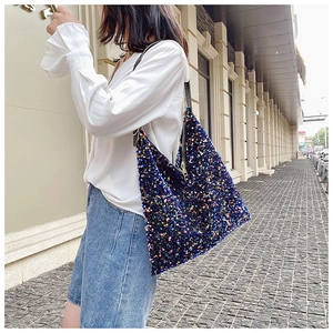 Detailed outdoor view of a large sequin tote bag with colorful embroidery and black leather strap