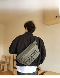 Détail du sac bandoulière en toile vert olive avec plusieurs poches zippées fonctionnelles
