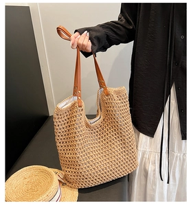 Detail of woven straw tote bag with brown leather handles and inner lining