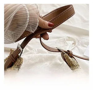 Detailed view of natural straw tote bag with brown leather handle and white stitching