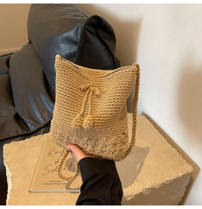 Detailansicht der khakifarbenen Häkeltasche mit Kordelzug und kugelförmigen Ornamenten
