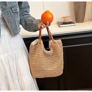 Detail of handmade straw woven tote bag featuring leather handles and hollow mesh texture