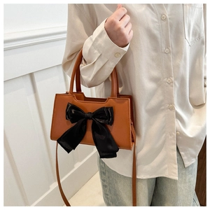 Sac bandoulière en similicuir marron avec un grand nœud en satin noir sur le devant